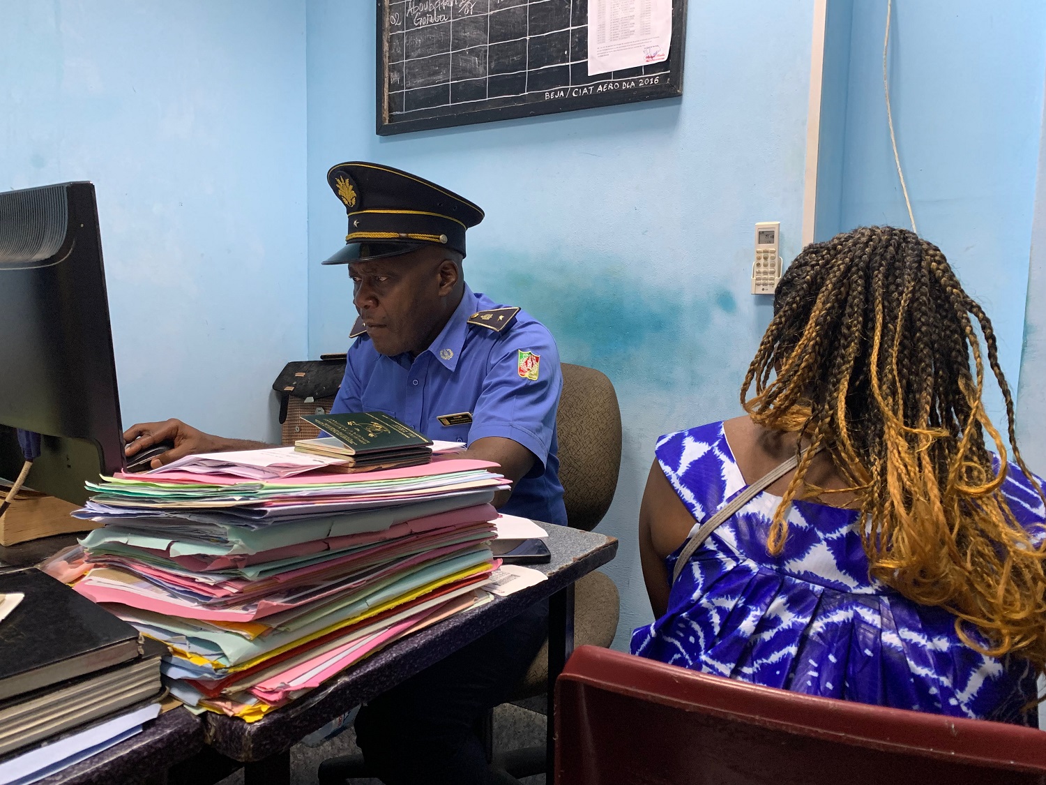 Un membre de la police Camerounaise vérifie les détails liés au parcours migratoire lors de l’arrivée à Douala. Photo : OIM 2022/Kim Winkler