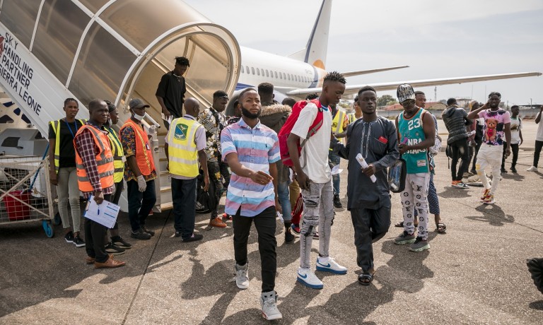 L’OIM fournit une aide après l’arrivée aux migrants de retour à l’aéroport international de Freetown. Crédit photo : OIM/Alfred Fornah)