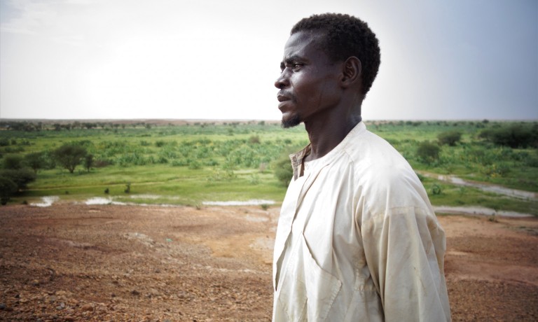 Boyi, 26, stares off into the distance over the 30 hectares of land that he now shares with other 29 community members. Photo: IOM/Monica Chiriac